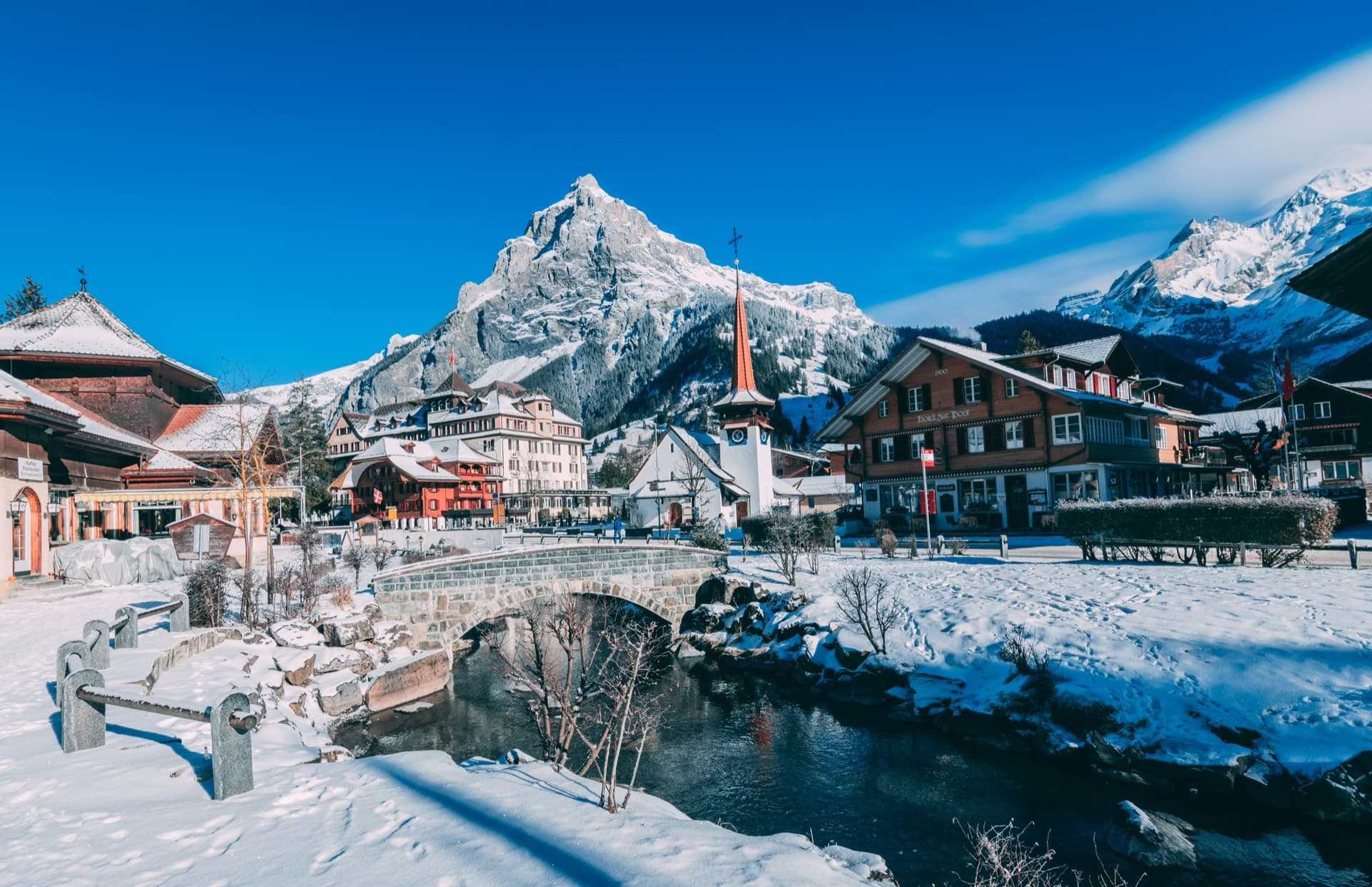 Snow-covered Swiss alpine village with traditional chalets below a mountain peak